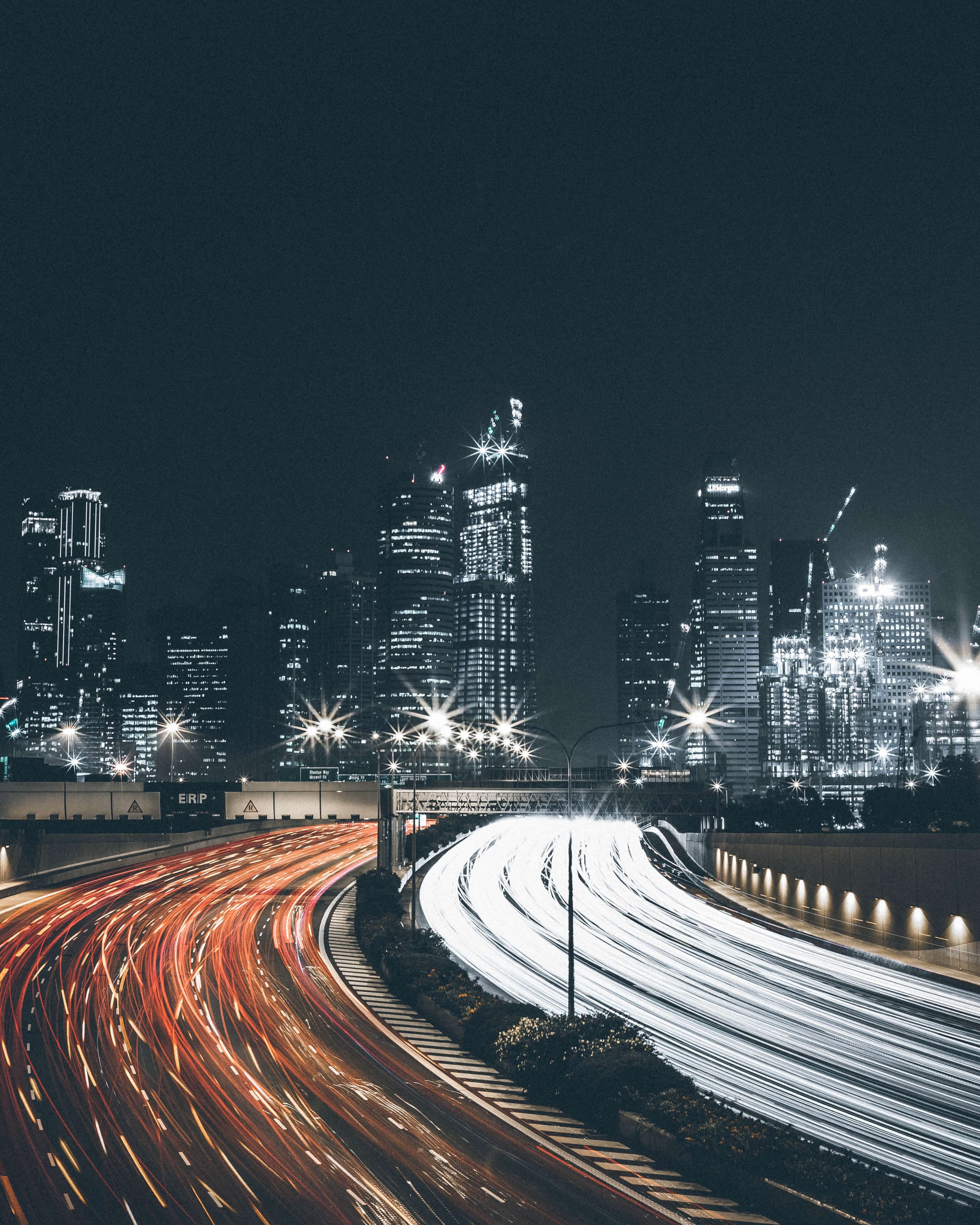Nighttime view of interstate traffic flowing in both directions toward a city skyline, symbolizing movement and direction